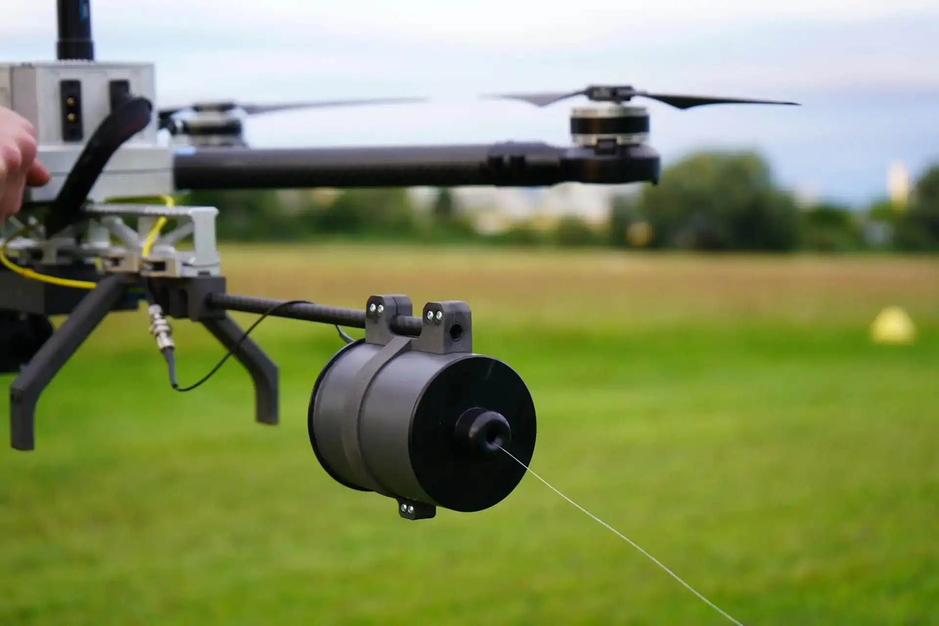 A fiber-optic FPV drone trails a hair-thin glass filament. With no radio link, there is nothing for jammers to detect. (Forbes)