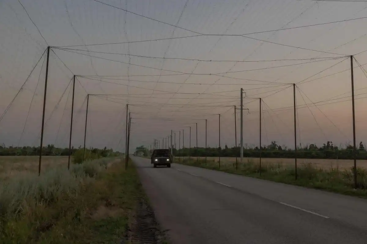 Nets shroud supply roads for kilometers, catching FPV drones before they reach the vehicles below. © Roman PILIPEY / AFP